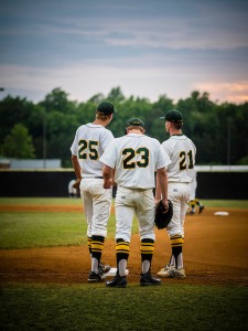 Drei junge Baseball-Spieler vor einem Sonnenuntergang